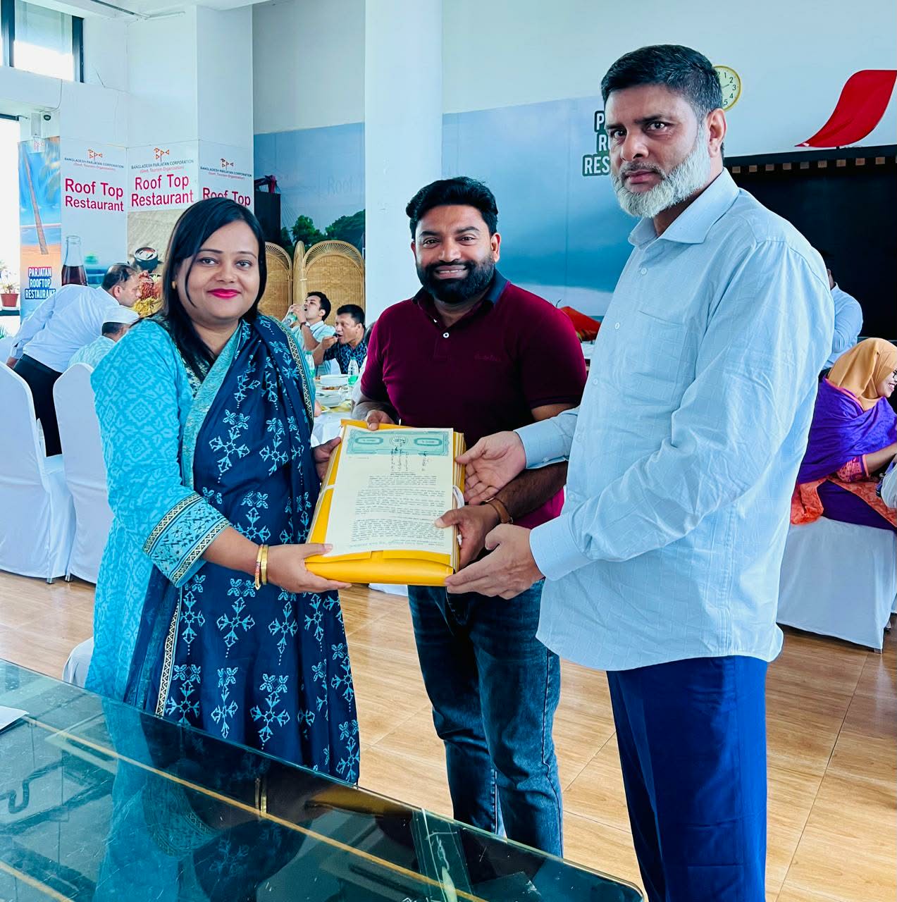 Three people presenting property documents at an indoor gathering