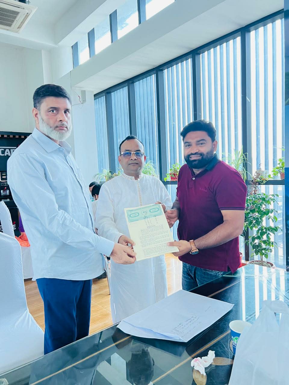 Three people displaying property documents during an indoor meeting